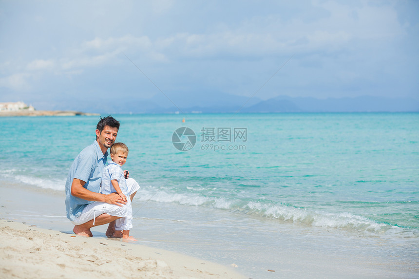 快乐的父亲和儿子在海滩玩耍喜悦爸爸微笑自由乐趣孩子海洋男人天空蓝色图片