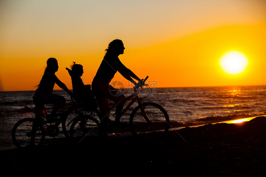 骑自行车的妈妈和孩子 在车轮上儿子女性女士海滨橙子海岸喜悦快乐乐趣女孩图片