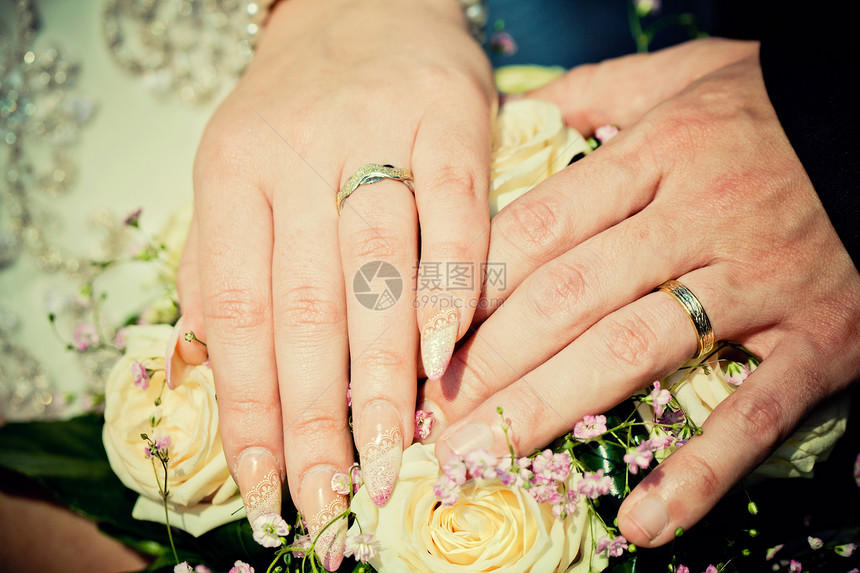新娘和新郎的手 用婚礼花束图片
