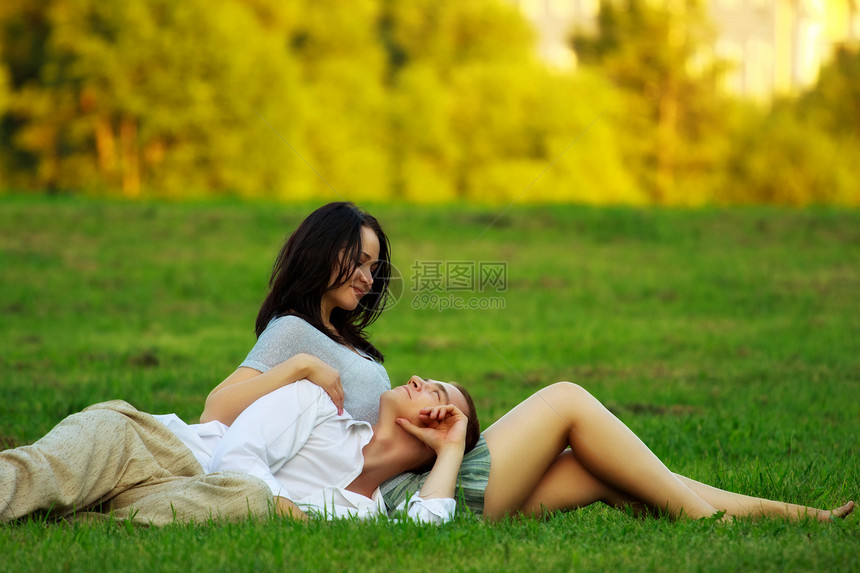 一对夫妇躺在公园草坪上衬套照片喜悦衬衫黄鼠狼蓝色投标幸福女孩草地图片