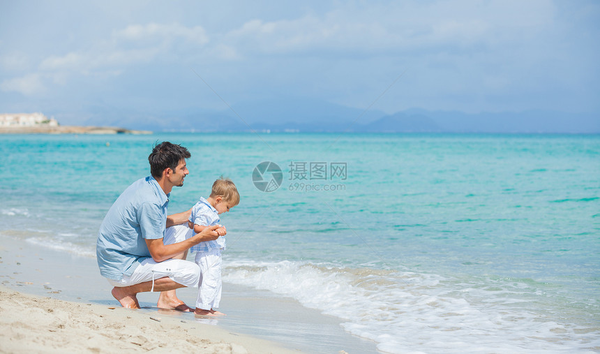 快乐的父亲和儿子在海滩玩耍孩子男生男性乐趣家庭假期海洋天空蓝色男人图片