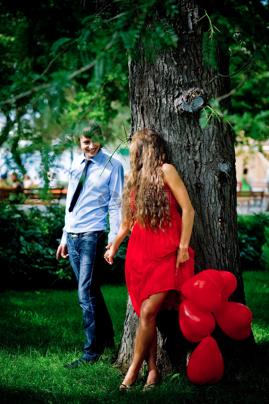 在树旁绿公园接吻的年轻夫妇图片