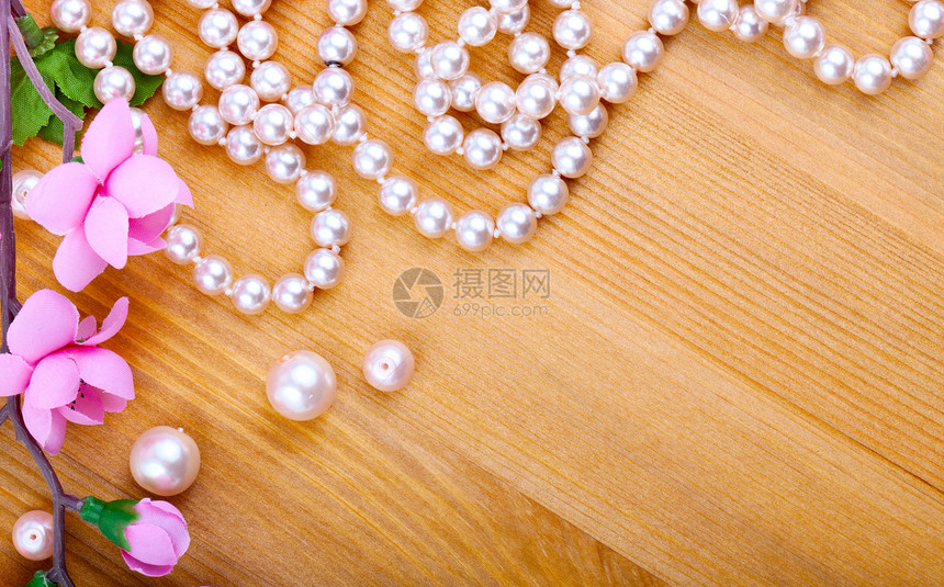 木制背景的人工珍珠和粉红花图片