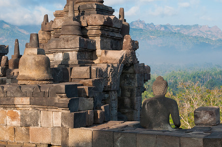 印度尼西亚中爪哇博罗布杜尔寺废墟沉思佛塔上帝建筑学岩石面孔雕塑日出寺庙背景