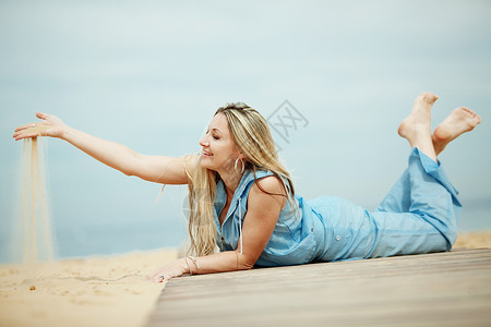 蓝色头发女人睡在沙滩上闲暇女性休息海滩快乐喜悦头发假期女士金发背景