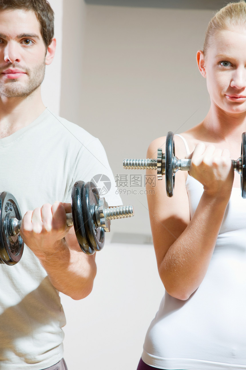男人和女人在健身房举起哑铃金发男人肌肉健身锻炼两个人体操两人夫妻权重图片