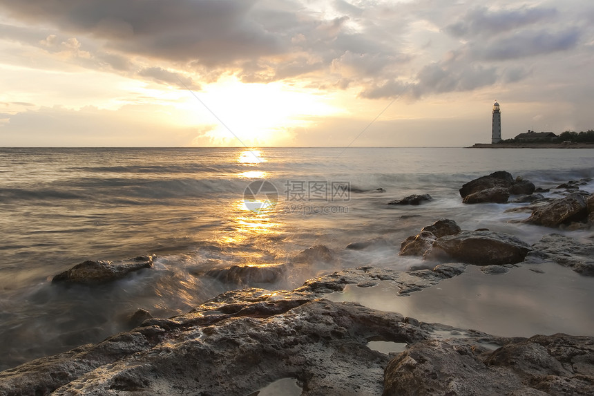 日落时的美丽的岩石海滨沙滩 有灯塔戏剧性安全房子导航蓝色海岸海岸线海洋光束风暴图片