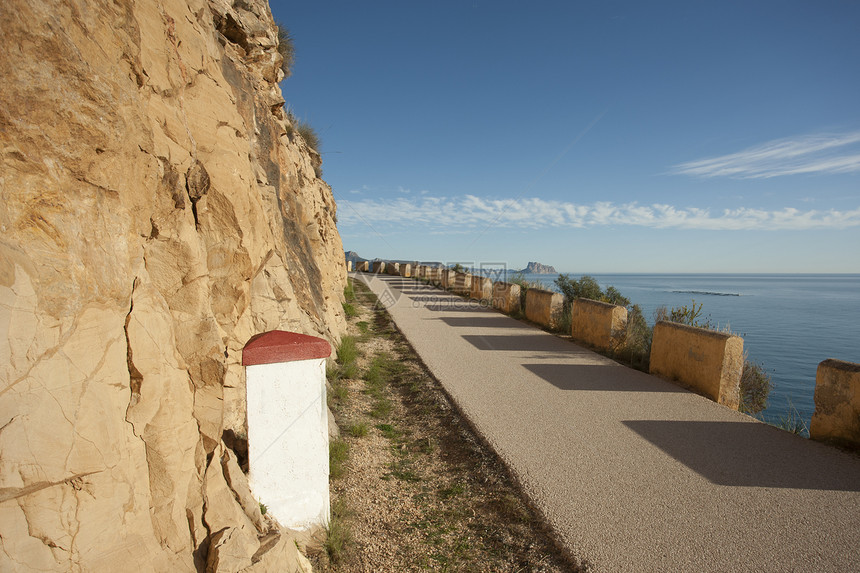 窄路沥青上坡阳光岩石石头海洋海岸里程碑晴天水平图片