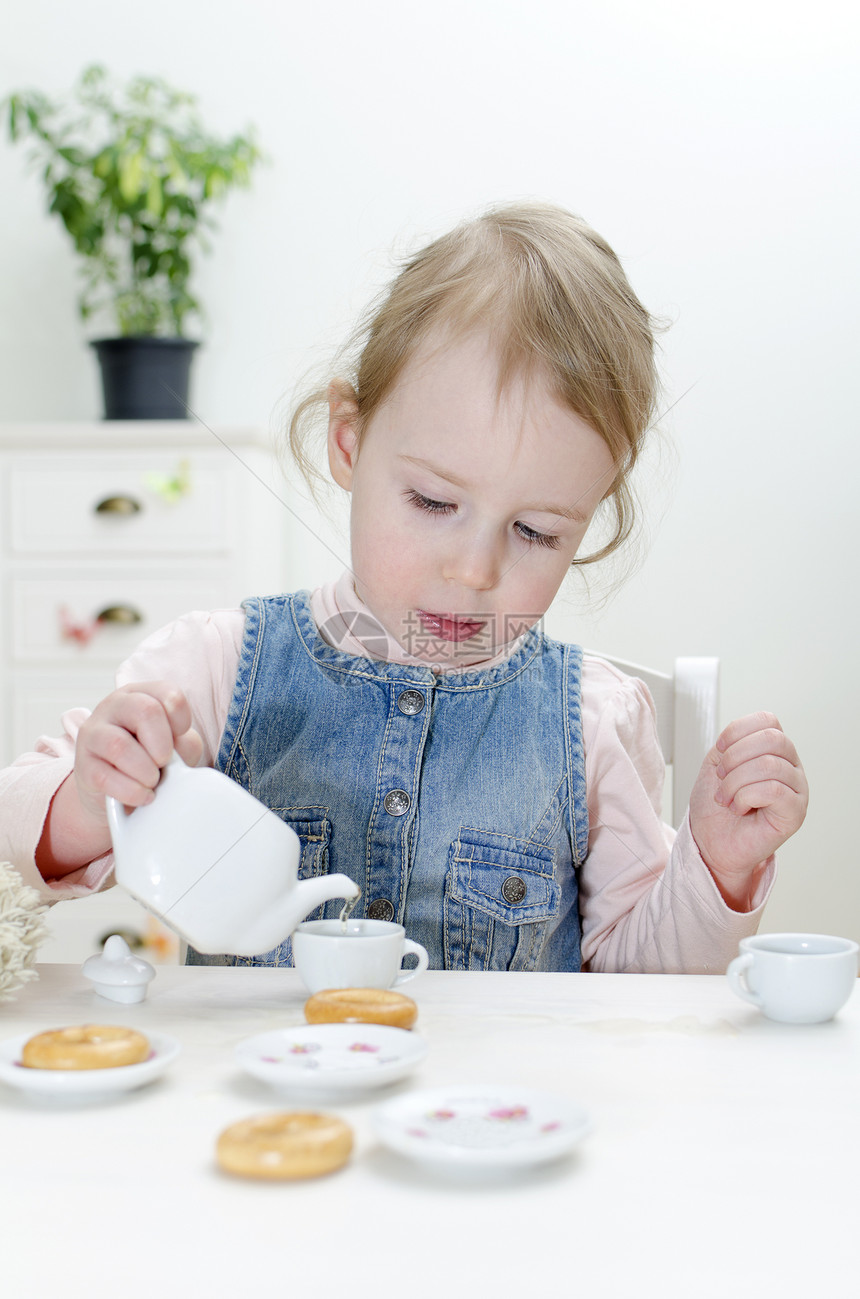 可爱的小女孩喝茶加百吉饼图片