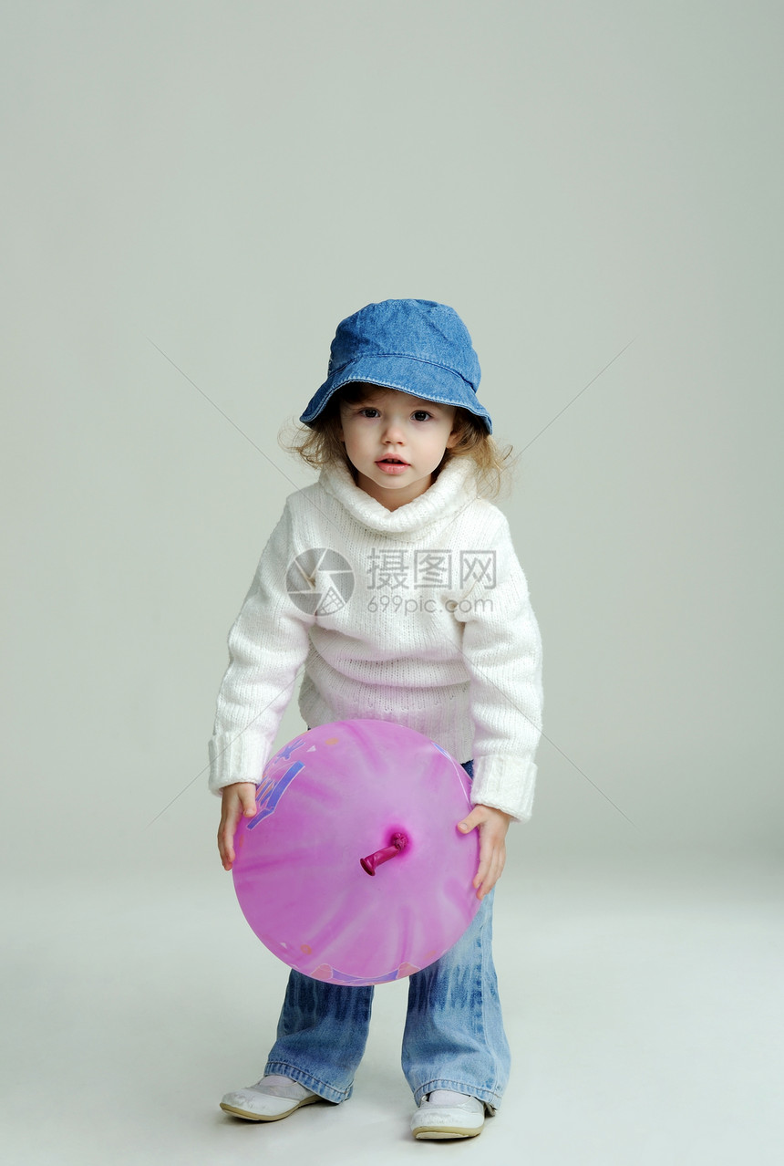 带气球的女孩头发蓝色地面乐趣帽子牛仔裤童年闲暇白色毛衣图片