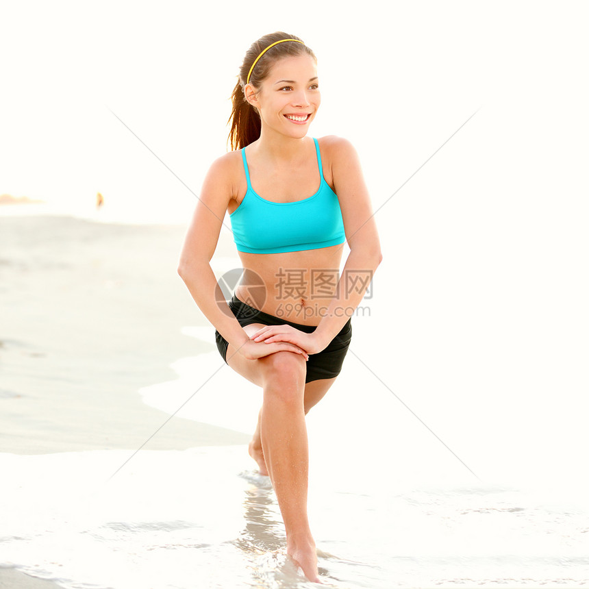 运动妇女伸展在海滩上图片