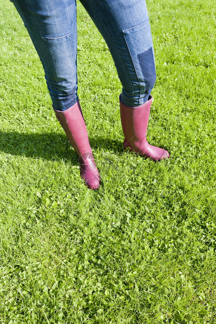 女性在草坪上穿着橡胶靴子的详情牛仔裤女士鞋类紫色成人外观牛仔布草地裤子图片