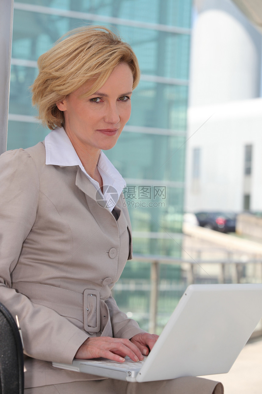 机场外膝上型电脑上的女商务人士工作销售量经理金发女士头发旅行导演套装女性图片