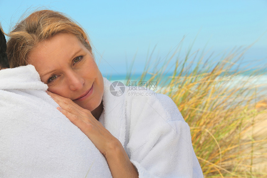 女人在海边放松浴衣海洋蓝色微笑倾斜毛巾天空温泉女士海滩图片