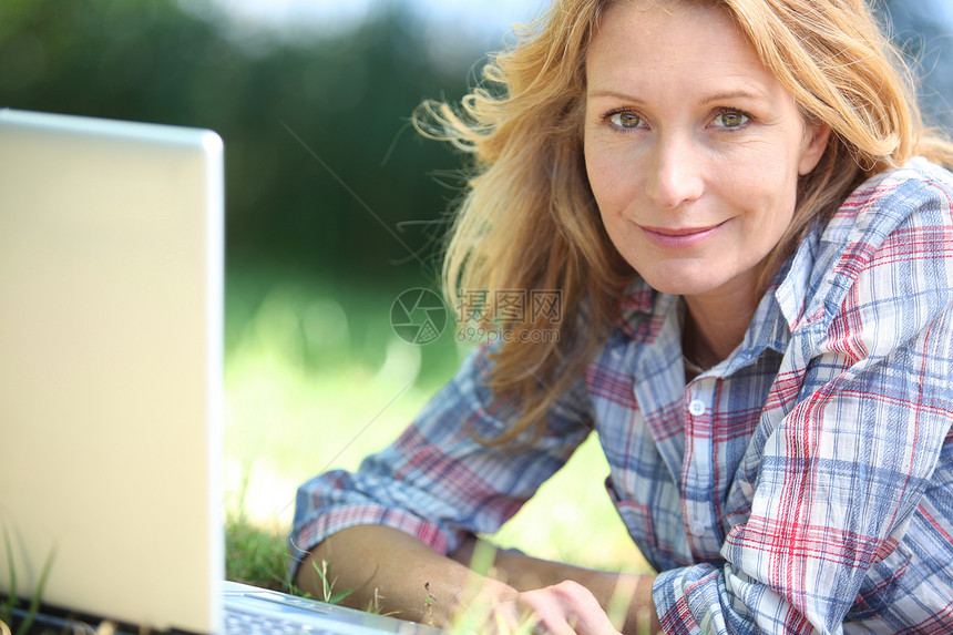 在公园使用膝上型计算机的妇女场地农村说谎母亲互联网成人技术中年人女性上网图片