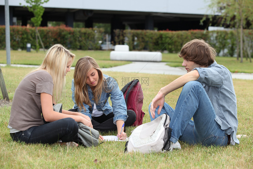 三名学生在草地上学习瞳孔家庭作业写作学校大学青少年校园课程男性男生图片