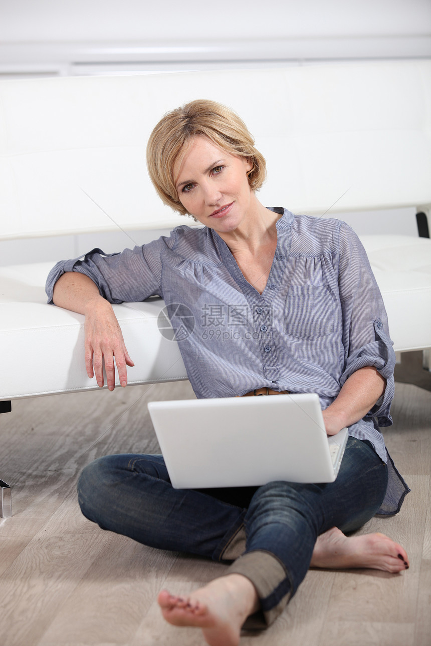 用笔记本电脑赤脚坐在地上的妇女图片