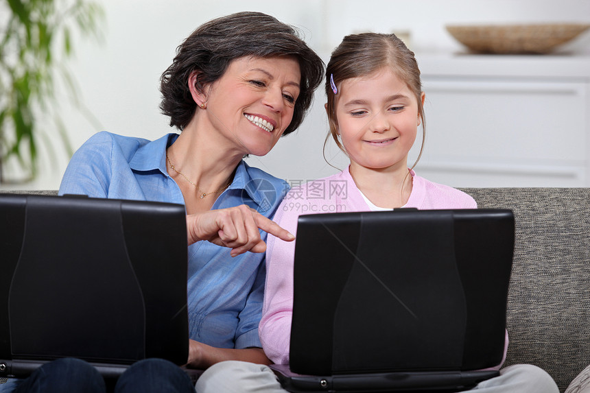 一个母亲和她的女儿 在他们的笔记本电脑上图片