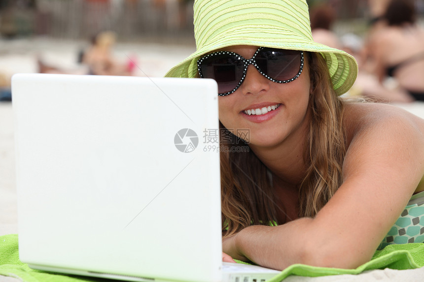 使用笔记本电脑在海滩上的妇女图片