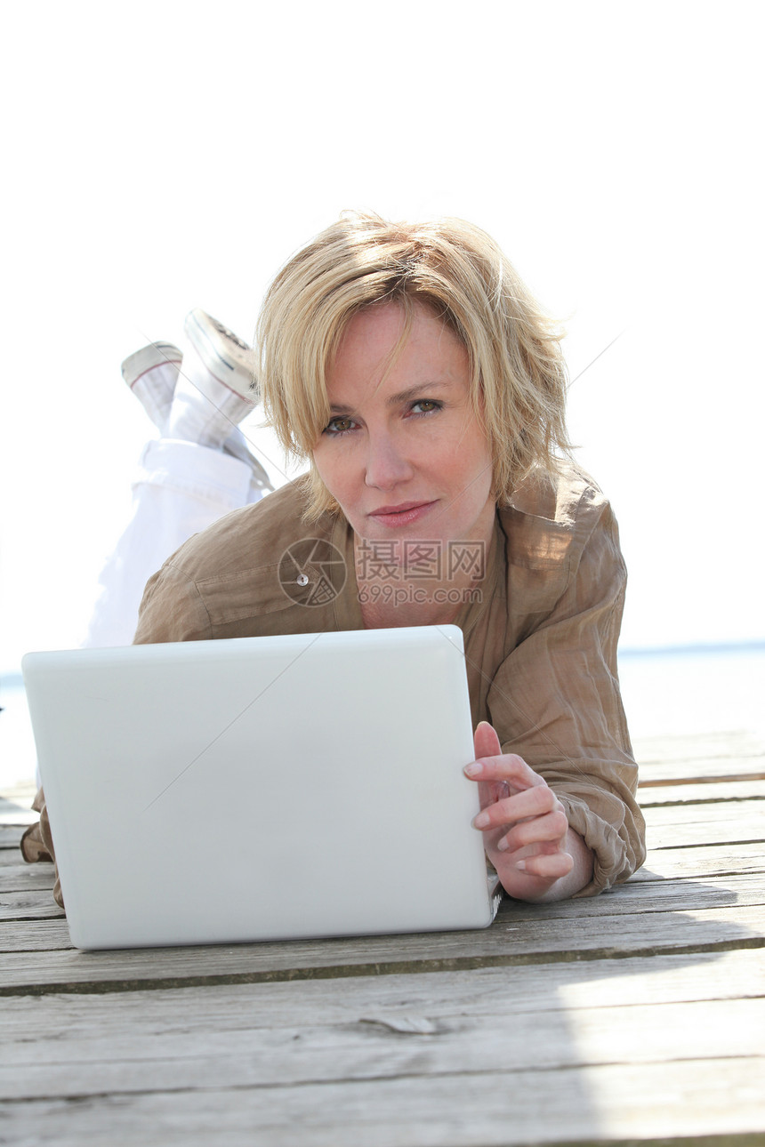 妇女在外面的笔记本电脑上作家想像力金发思维白色写作女性地面码头图片