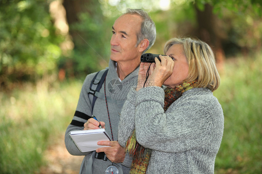 在森林中用望远镜观察野生生物的几对退休人员图片