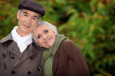 公园里的一对成熟夫妇夫妻老年男人退休乐趣牙齿帽子女士情人树木背景图片