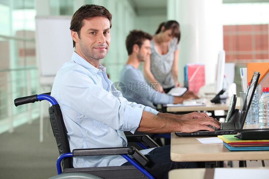 使用膝上型电脑的轮椅雇员笔记本衣服办公室男人同事员工桌子商业团结工作图片