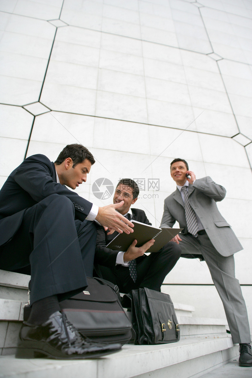坐在城市大楼外面的商务人士们图片