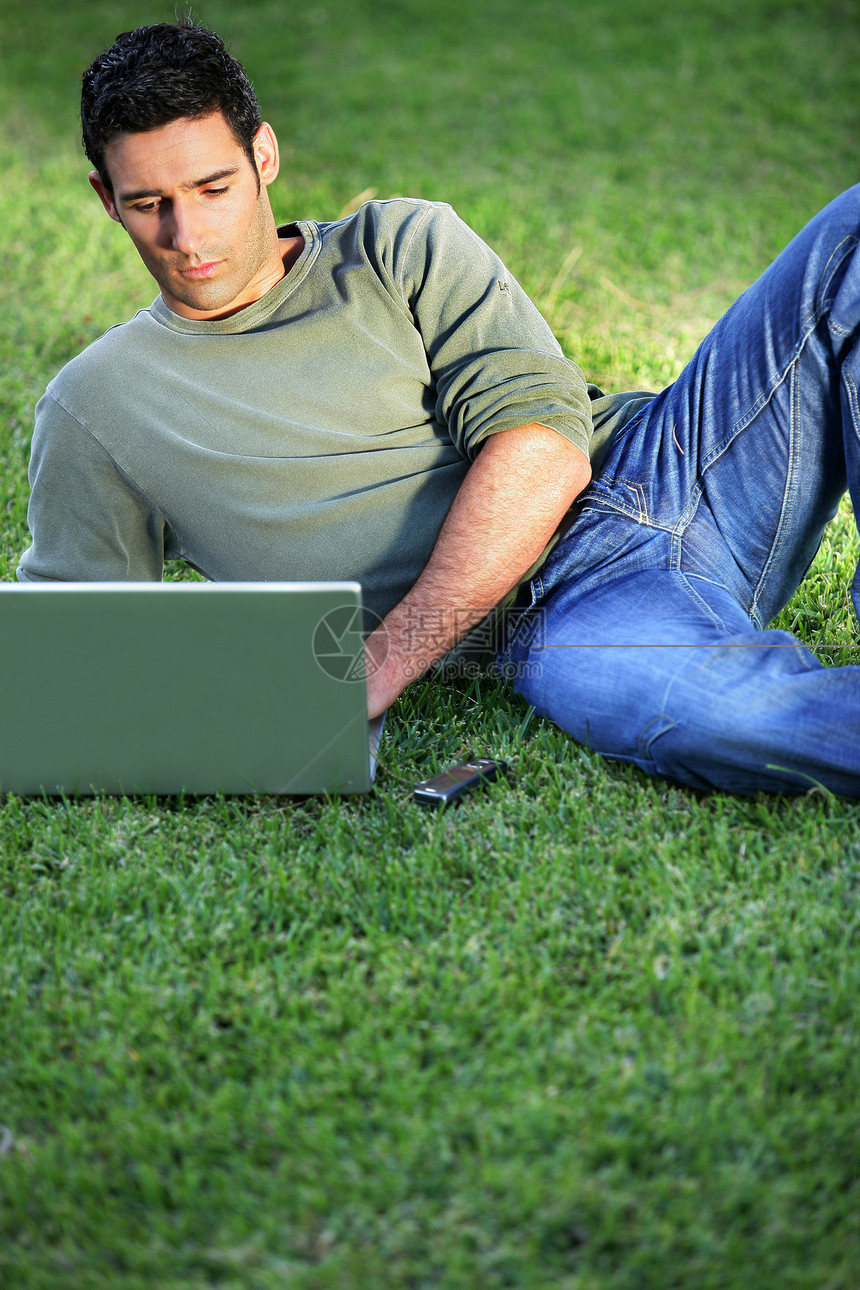 在笔记本电脑前躺在草地上的人生意人蓝色人士职业互联网教育学习时间报告场地图片