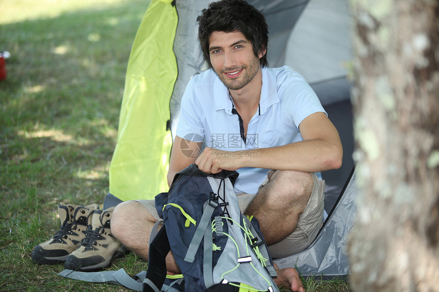 男人坐在帐篷前的人图片