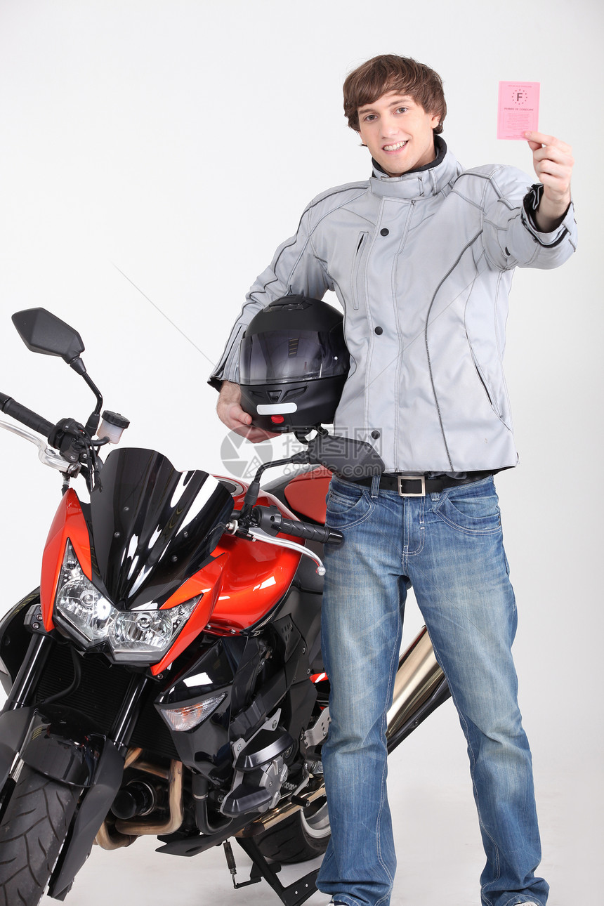 持有驾照的年轻人站在摩托车旁边 紧靠摩托车图片