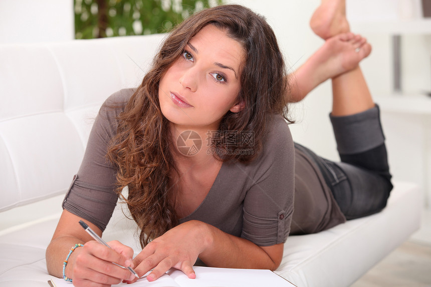 年轻女人躺在沙发上写日记图片