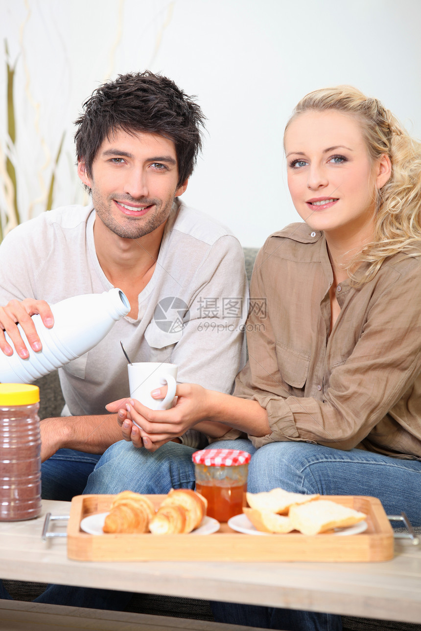一对夫妇在沙发上吃早餐微笑幸福牛奶休息室男朋友咖啡桌子女性男性情人图片