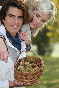 采摘栗子的夫妇女士围巾男人夫妻种子水果毛皮地面微笑柳条背景图片