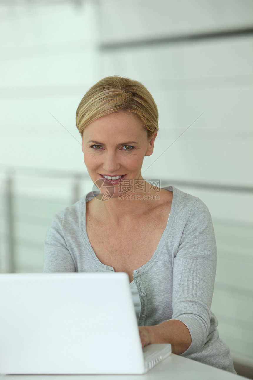 手提笔记本电脑上的妇女微电脑学习资讯中年全世界全球小型机白色桌子电子商务图片