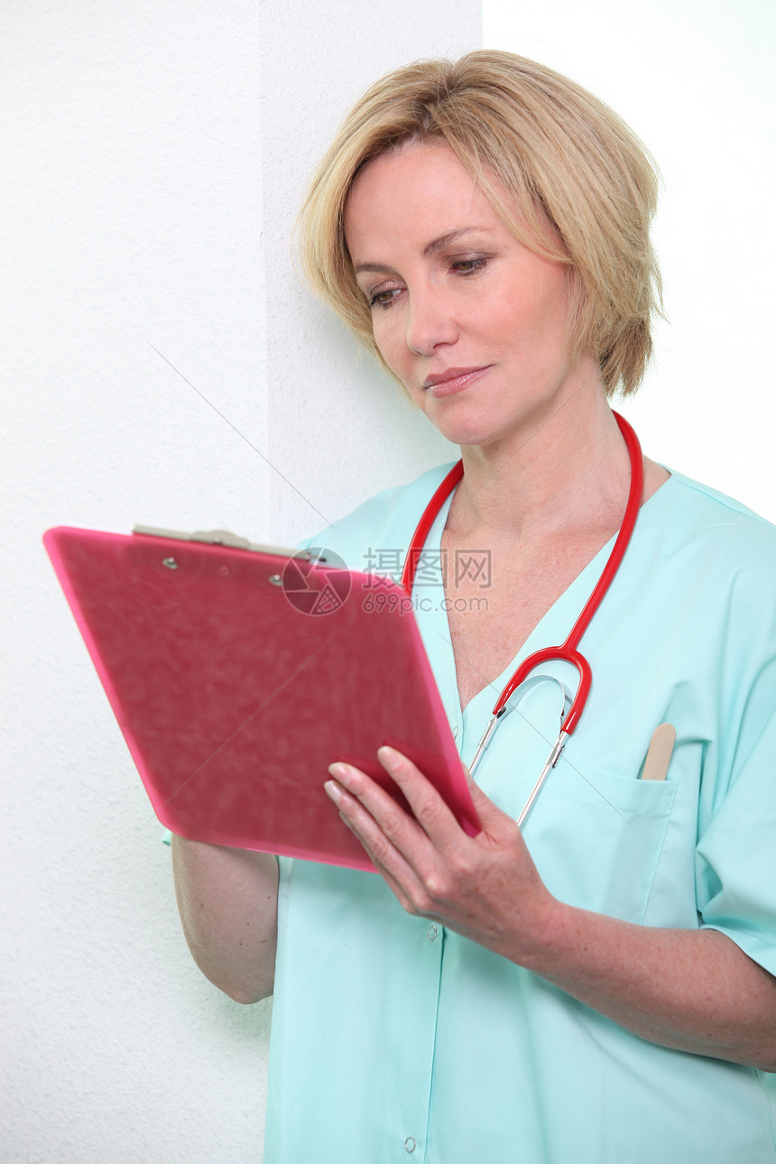 女医生在剪贴板上做笔记医疗专注蓝色写作外套金发女性医院护士头发图片