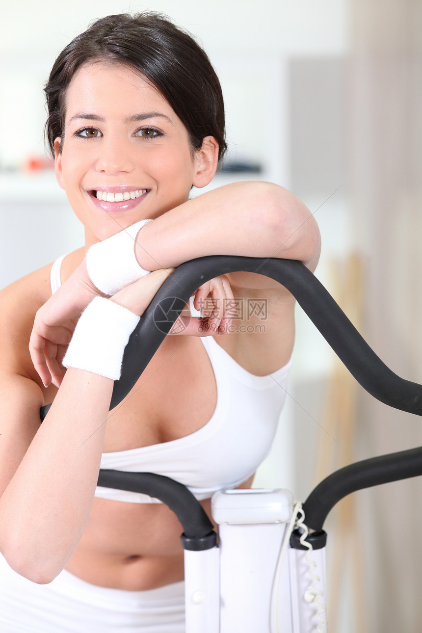 女人在健身房休息仪器机器运动服疲劳女士绳索微笑倾斜活力身体图片