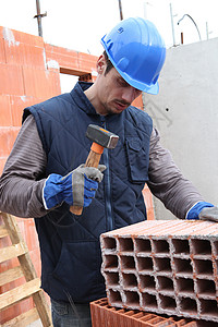建筑工地上的梅森石工石匠男人建设者蓝领修理瓦工砖墙工人锤子背景图片