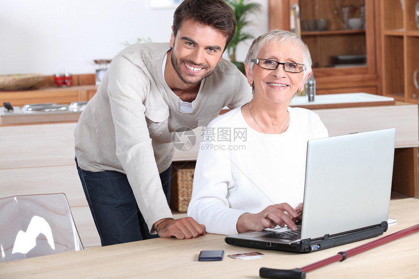 年轻男子用笔记本电脑计算帮助年长妇女图片