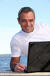 40岁男人在海后做电脑操作背景图片