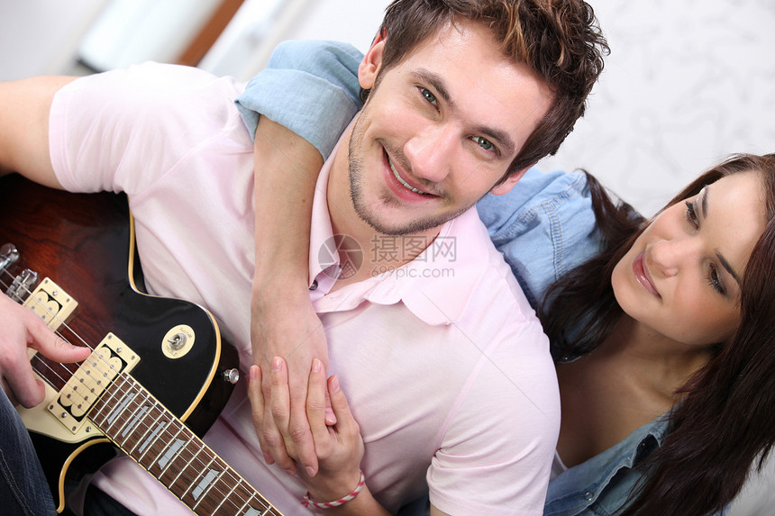 年轻夫妇在家里弹吉他娱乐韵律闲暇情人音乐吉他朋友水平女士微笑图片