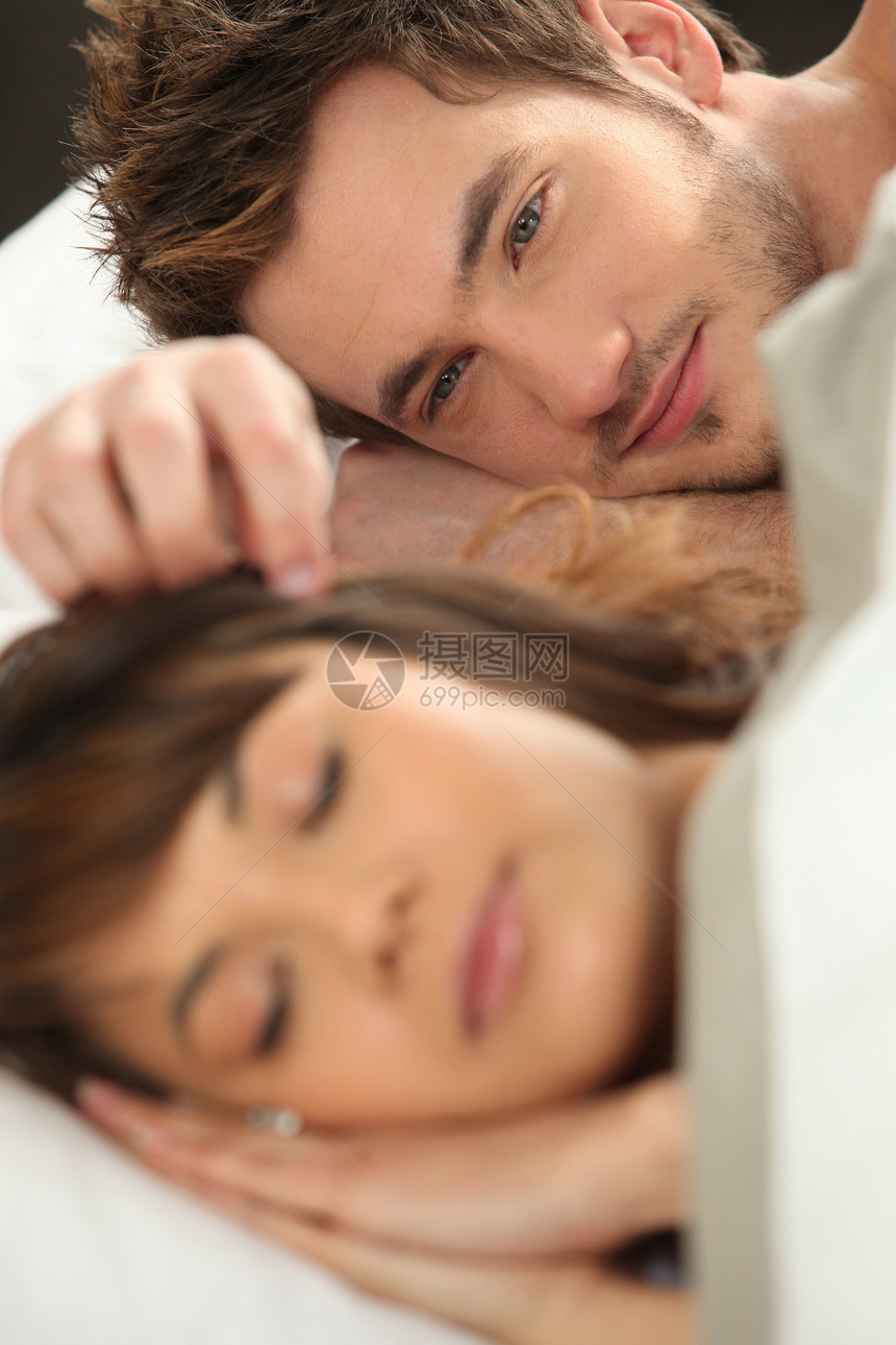 看着他的伴侣睡在床上的年轻人图片