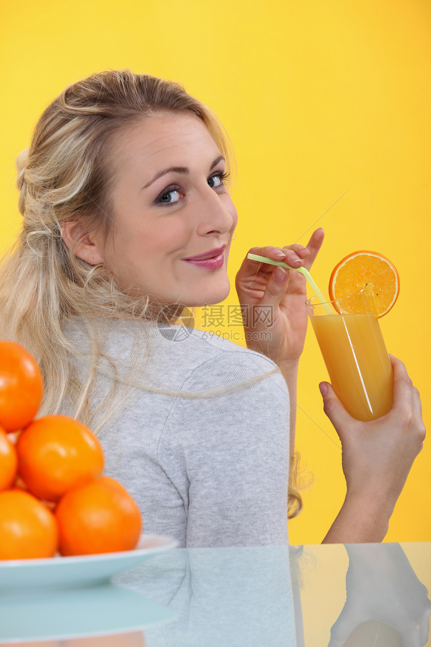 喝橙汁的金发女人休息室女士立方体苦乐冻结桌子玻璃果汁盘子稻草图片