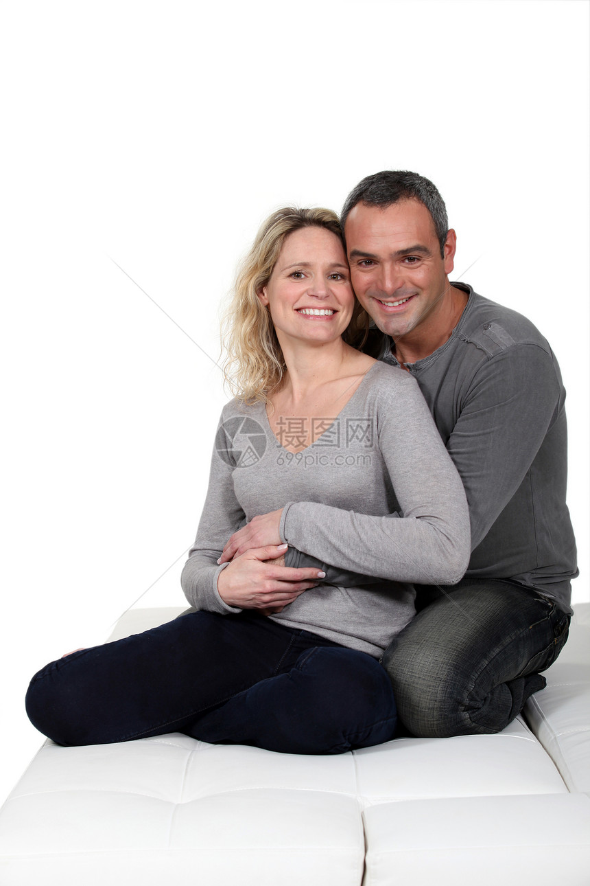 夫妻在沙发上拥抱快乐椅子妻子女士客厅丈夫投标微笑房间男性图片