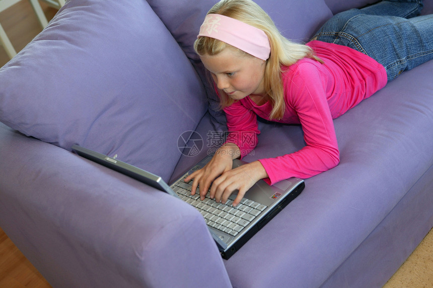 使用笔记本电脑的小女孩工作房子沙发女性生活学习互联网房间微笑童年图片