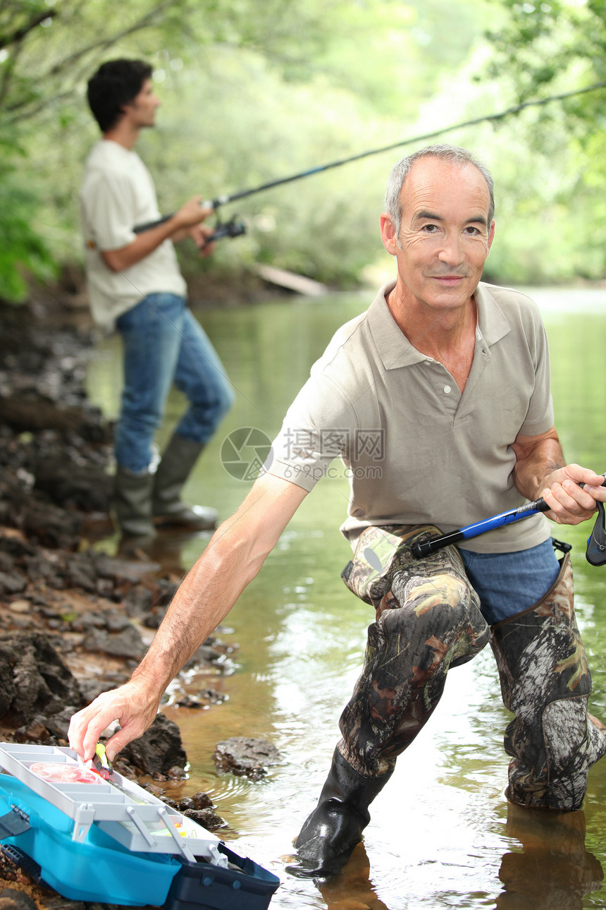 父亲和儿子捕鱼秃头家庭爱好池塘黑发溪流成套马球牛仔裤郊游图片