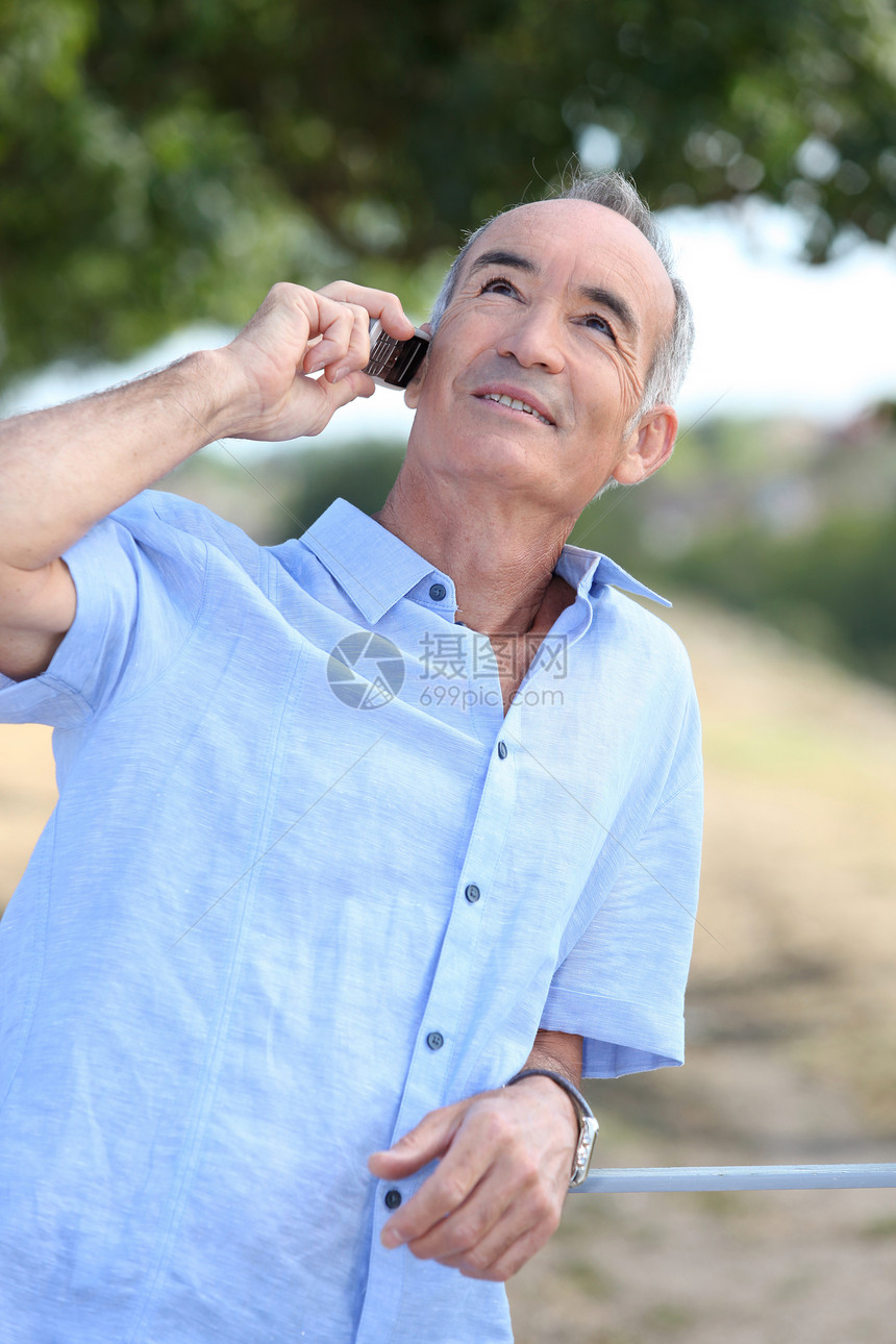 拥有移动电话的中年户外男子图片