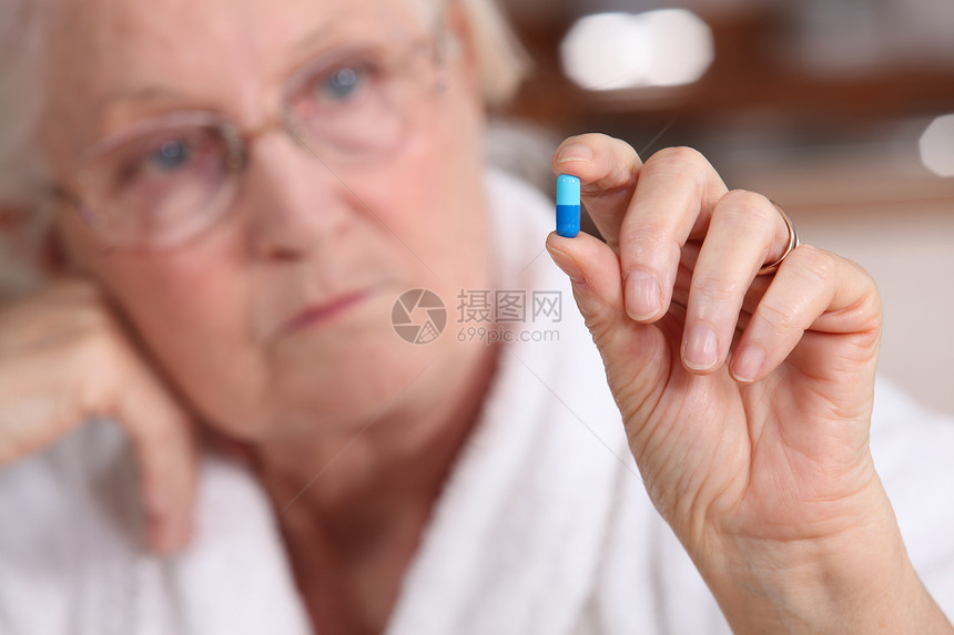 一个吃药的老妇人女士疾病退休止痛药疼痛药品手指胶囊展示眼镜图片
