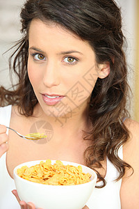 妇女早餐吃谷类食品营养勺子女士眼睛钻孔黑发头发食物背景图片
