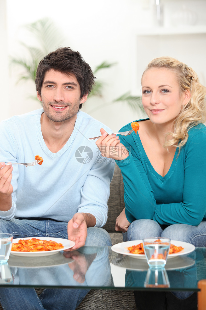 年轻夫妇在电视前吃饭图片